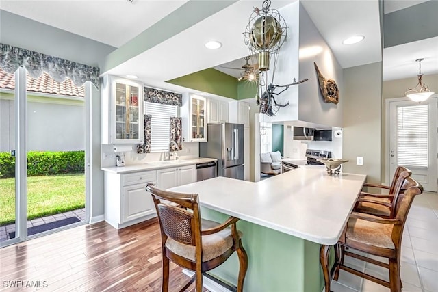 2799 Jude Island Way, Naples, FL 34119 - kitchen with appliances with stainless steel finishes, a breakfast bar area, glass insert cabinets, white cabinetry, and light countertops