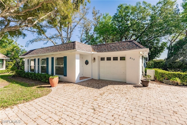217 Yorkshire Ct Unit 2, Naples, FL 34112 - view of front facade with an attached garage, stucco siding, decorative driveway, and roof with shingles