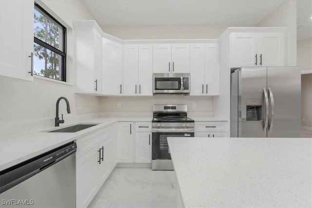 915 Anthony St E, Lehigh Acres, FL 33974 - kitchen featuring appliances with stainless steel finishes, light marble finish flooring, and white cabinets