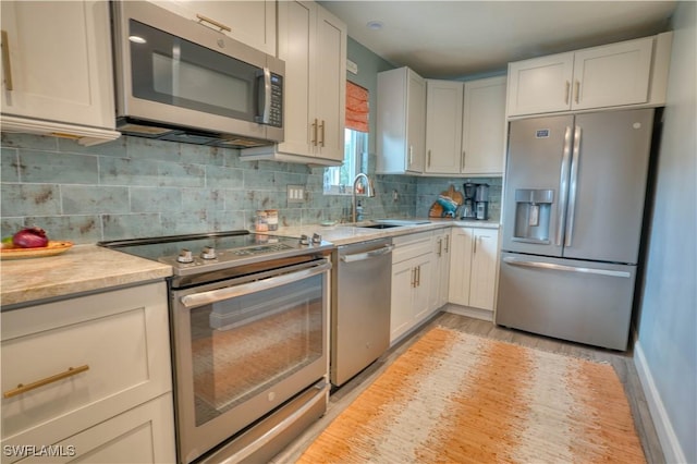 6008 Cypress Ln, Bonita Springs, FL 34134 - kitchen featuring appliances with stainless steel finishes, light countertops, light wood-style floors, tasteful backsplash, and white cabinets