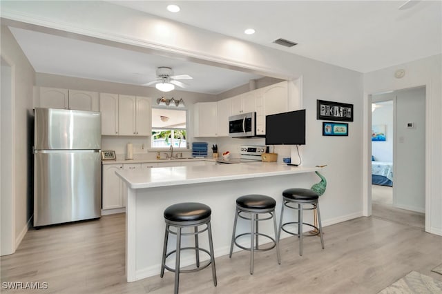 1308 Hull St S, Gulfport, FL 33707 - kitchen with appliances with stainless steel finishes, a breakfast bar, white cabinets, a peninsula, and recessed lighting