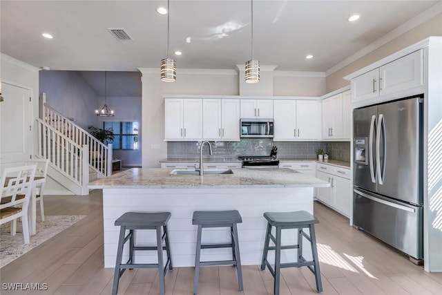 14712 Kingfisher Loop, Naples, FL 34120 - kitchen with appliances with stainless steel finishes, ornamental molding, tasteful backsplash, white cabinets, and light stone counters
