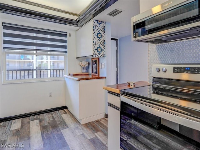 4431 Bay Beach Ln Unit 522, Fort Myers Beach, FL 33931 - kitchen with stainless steel electric range, exhaust hood, wood counters, decorative backsplash, and light wood-style flooring