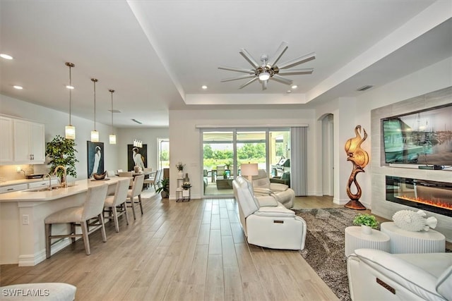 3649 Avenida Del Vera, North Fort Myers, FL 33917 - living room with a ceiling fan, light wood finished floors, a tray ceiling, recessed lighting, and a glass covered fireplace