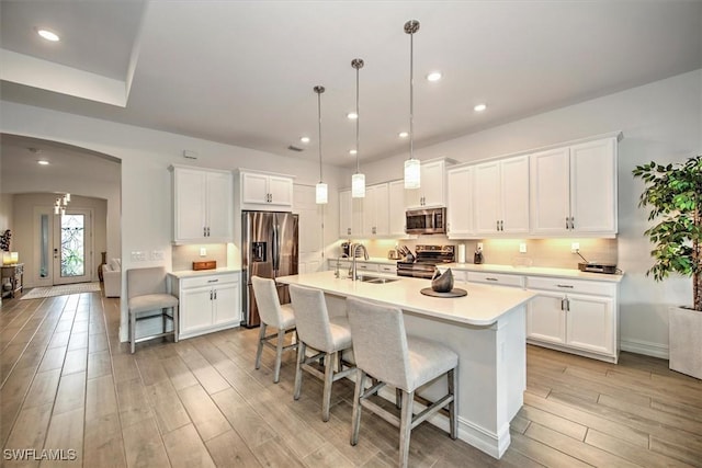 3649 Avenida Del Vera, North Fort Myers, FL 33917 - kitchen featuring appliances with stainless steel finishes, light wood-style flooring, arched walkways, a breakfast bar, and white cabinetry