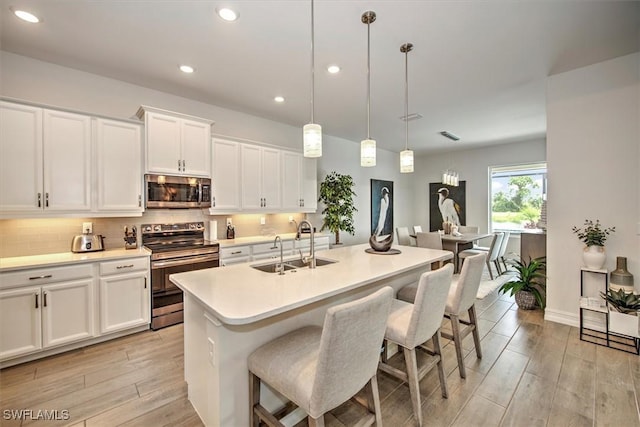 3649 Avenida Del Vera, North Fort Myers, FL 33917 - kitchen featuring appliances with stainless steel finishes, light wood-style floors, white cabinets, recessed lighting, and a breakfast bar area