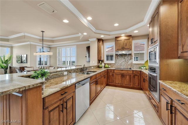 580 El Camino Real Unit 3606, Naples, FL 34119 - kitchen with stainless steel appliances, a tray ceiling, brown cabinets, decorative backsplash, and a peninsula