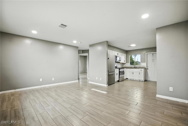 125/127 Gordon Ave S, Lehigh Acres, FL 33973 - unfurnished living room with light wood-type flooring and recessed lighting
