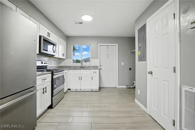 125/127 Gordon Ave S, Lehigh Acres, FL 33973 - kitchen with stainless steel appliances, white cabinetry, and light stone counters