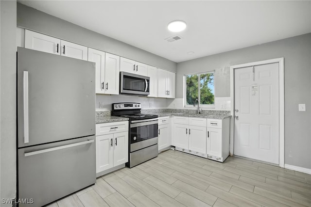 125/127 Gordon Ave S, Lehigh Acres, FL 33973 - kitchen featuring stainless steel appliances, white cabinets, light stone countertops, and backsplash