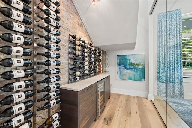 745 Riviera Dr, Naples, FL 34103 - wine room with light wood-style floors, brick wall, lofted ceiling, and beverage cooler
