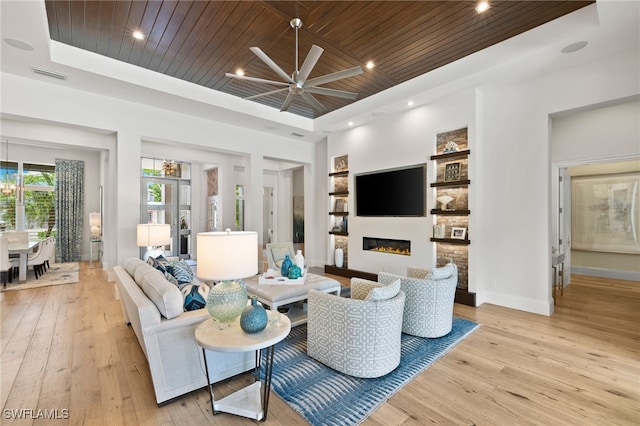 745 Riviera Dr, Naples, FL 34103 - living room with a tray ceiling, wood ceiling, light wood finished floors, a ceiling fan, and a glass covered fireplace