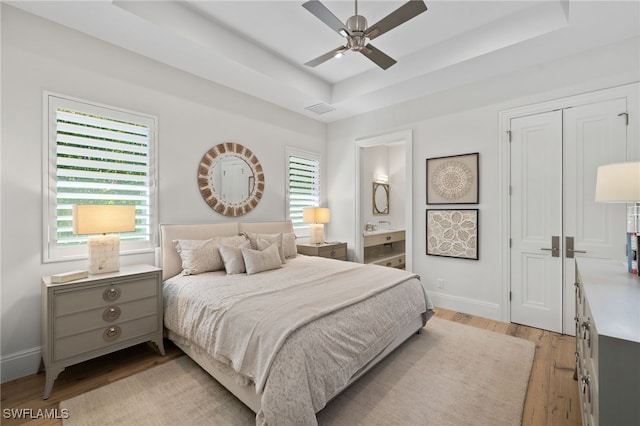 745 Riviera Dr, Naples, FL 34103 - bedroom with a raised ceiling, light wood-style floors, ensuite bath, and a ceiling fan