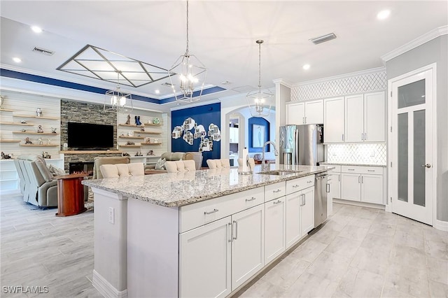 2110 Antigua Ln, Naples, FL 34120 - kitchen with appliances with stainless steel finishes, crown molding, arched walkways, decorative backsplash, and an island with sink
