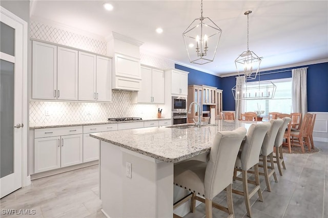 2110 Antigua Ln, Naples, FL 34120 - kitchen with a chandelier, appliances with stainless steel finishes, crown molding, a kitchen island with sink, and a kitchen bar