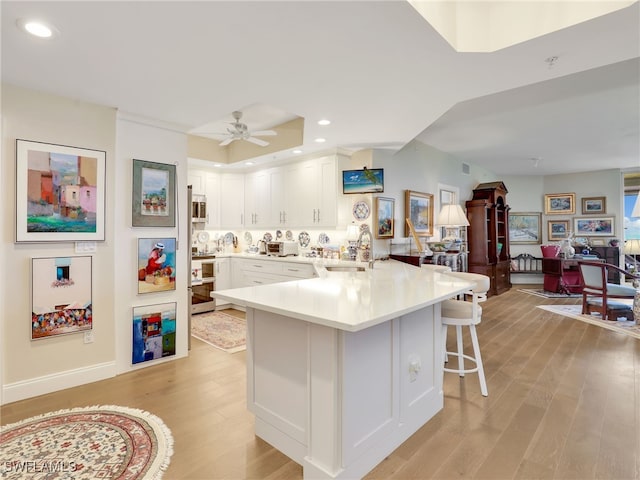 1001 Arbor Lake Dr Unit 1102, Naples, FL 34110 - kitchen featuring a breakfast bar, a peninsula, light wood finished floors, white cabinets, and open floor plan