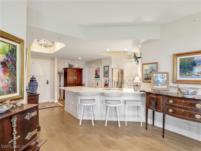 1001 Arbor Lake Dr Unit 1102, Naples, FL 34110 - kitchen with stainless steel fridge, light wood-style flooring, a peninsula, a kitchen bar, and light countertops