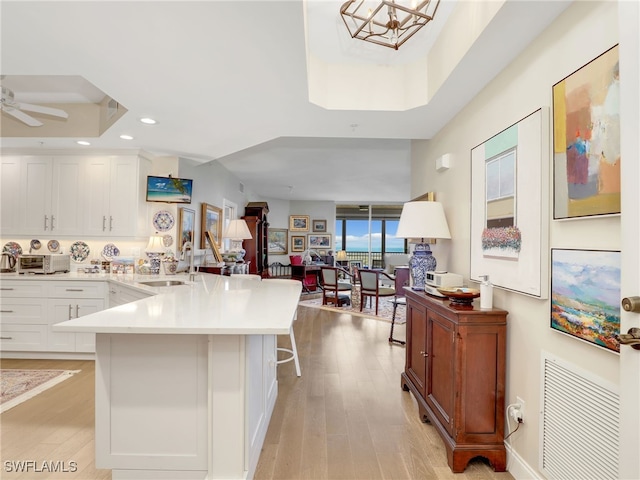 1001 Arbor Lake Dr Unit 1102, Naples, FL 34110 - kitchen with a peninsula, light wood finished floors, a kitchen bar, white cabinets, and recessed lighting