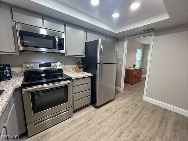 195 E Mariana Ave, North Fort Myers, FL 33917 - kitchen with stainless steel appliances, light wood-type flooring, a tray ceiling, gray cabinetry, and recessed lighting