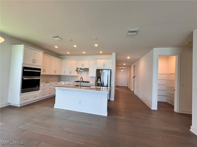 16106 Preservation Blvd, Punta Gorda, FL 33982 - kitchen with appliances with stainless steel finishes, under cabinet range hood, tasteful backsplash, dark wood-style flooring, and a kitchen island with sink
