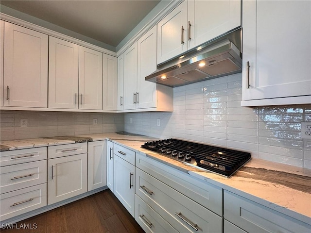 16106 Preservation Blvd, Punta Gorda, FL 33982 - kitchen featuring under cabinet range hood, stainless steel gas cooktop, dark wood finished floors, tasteful backsplash, and white cabinets
