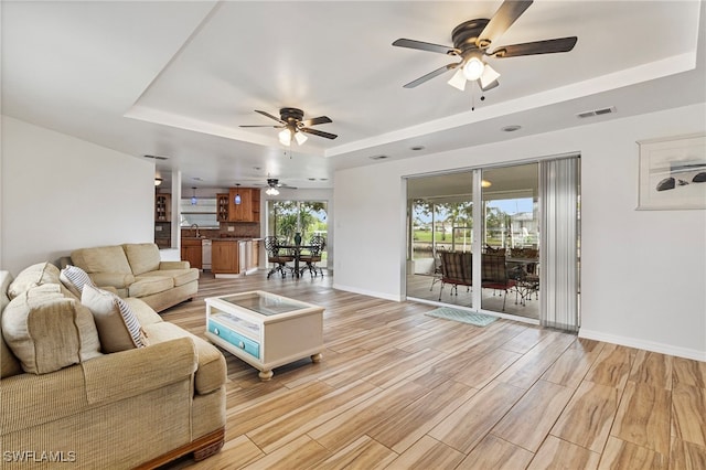138 Dowling Ave NE, Port Charlotte, FL 33952 - living room featuring a tray ceiling, a ceiling fan, and light wood-style flooring