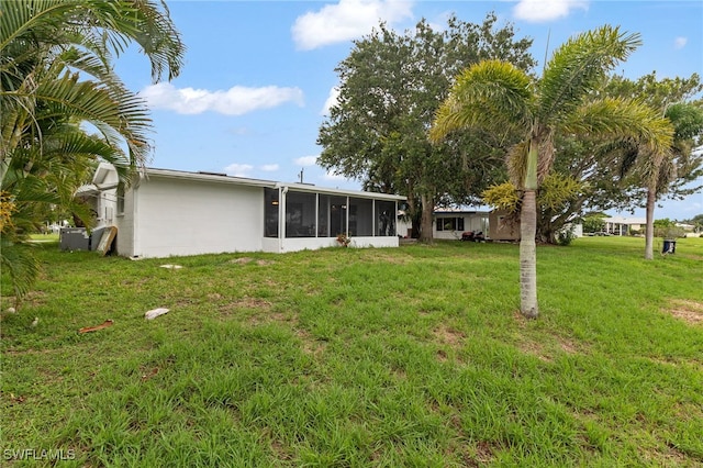 138 Dowling Ave NE, Port Charlotte, FL 33952 - rear view of property with a sunroom, a lawn, and concrete block siding