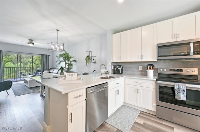 9175 Celeste Dr Unit 305, Naples, FL 34113 - kitchen with stainless steel appliances, open floor plan, light wood-style floors, backsplash, and a peninsula