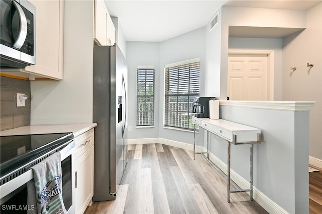 9175 Celeste Dr Unit 305, Naples, FL 34113 - kitchen with appliances with stainless steel finishes, light wood-style flooring, light countertops, white cabinets, and backsplash