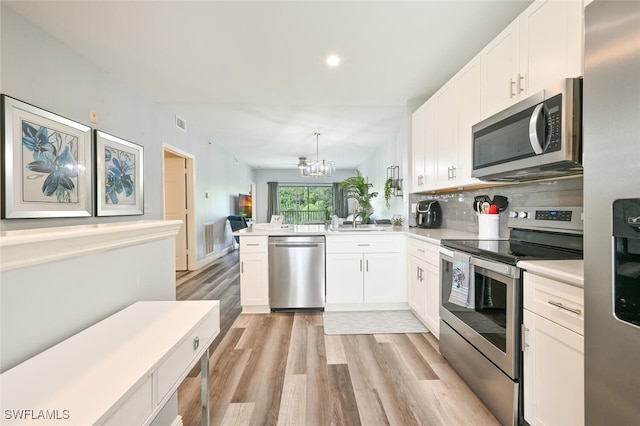 9175 Celeste Dr Unit 305, Naples, FL 34113 - kitchen featuring stainless steel appliances, light wood finished floors, a chandelier, light countertops, and white cabinets