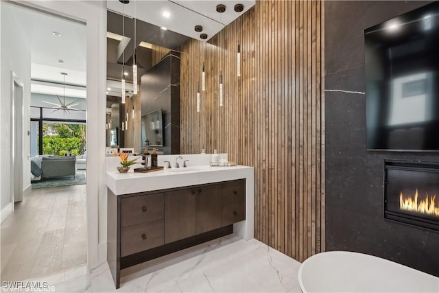 10411 Via Parma Way, Miromar Lakes, FL 33913 - full bathroom with vanity, a glass covered fireplace, wood walls, and marble finish flooring