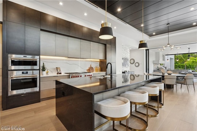 10411 Via Parma Way, Miromar Lakes, FL 33913 - kitchen with modern cabinets, a breakfast bar area, appliances with stainless steel finishes, recessed lighting, and open floor plan