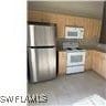 1207 Williams Ave, Lehigh Acres, FL 33972 - kitchen with freestanding refrigerator and brown cabinetry