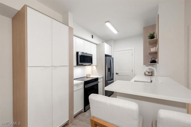 1170 Reserve Way Unit 107, Naples, FL 34105 - kitchen with appliances with stainless steel finishes, open shelves, a peninsula, white cabinets, and light wood-style floors