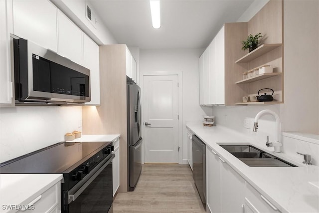 1170 Reserve Way Unit 107, Naples, FL 34105 - kitchen featuring stainless steel appliances, open shelves, white cabinets, light countertops, and light wood-type flooring