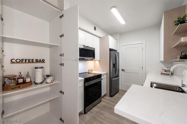 1170 Reserve Way Unit 107, Naples, FL 34105 - kitchen featuring open shelves, stainless steel appliances, light wood-type flooring, light countertops, and white cabinetry