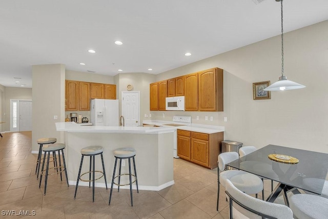 3781 Costa Maya Way Unit 101, Estero, FL 33928 - kitchen featuring white appliances, a breakfast bar area, light countertops, light tile patterned flooring, and recessed lighting