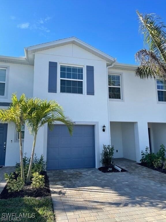 15141 Wildflower Cir, Naples, FL 34119 - view of front of house with stucco siding, decorative driveway, and an attached garage