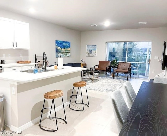 15141 Wildflower Cir, Naples, FL 34119 - kitchen featuring white cabinetry, light countertops, a kitchen breakfast bar, light tile patterned floors, and a kitchen island with sink