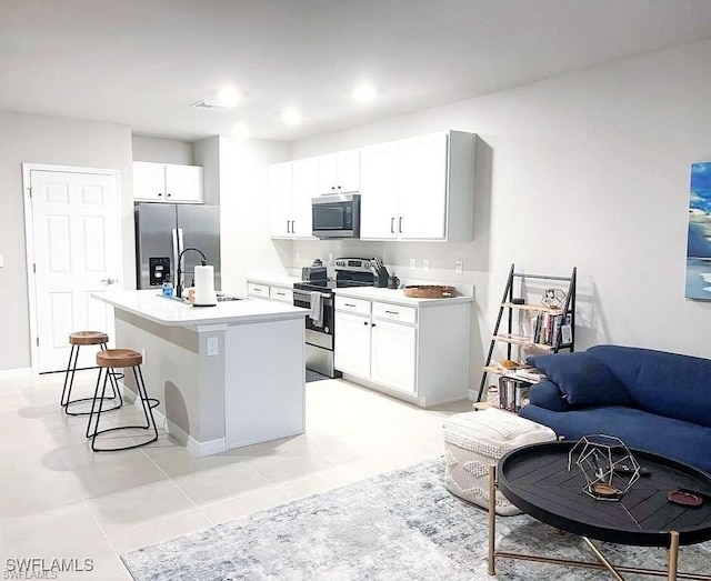 15141 Wildflower Cir, Naples, FL 34119 - kitchen with appliances with stainless steel finishes, a breakfast bar, a kitchen island with sink, white cabinets, and light tile patterned floors