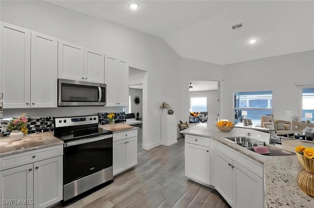 2922 20th St SW, Lehigh Acres, FL 34120 - kitchen with stainless steel appliances, lofted ceiling, open floor plan, light countertops, and light wood-type flooring