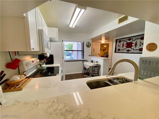 5735 Foxlake Dr Unit 1, North Fort Myers, FL 33917 - kitchen with white appliances, white cabinets, and dark wood finished floors