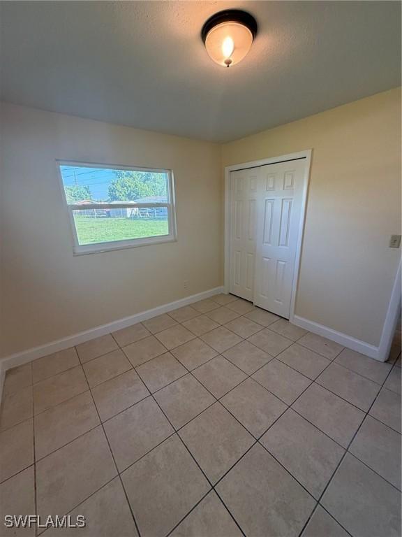 401 W Oregon Rd, Lehigh Acres, FL 33971 - unfurnished bedroom featuring light tile patterned floors and a closet