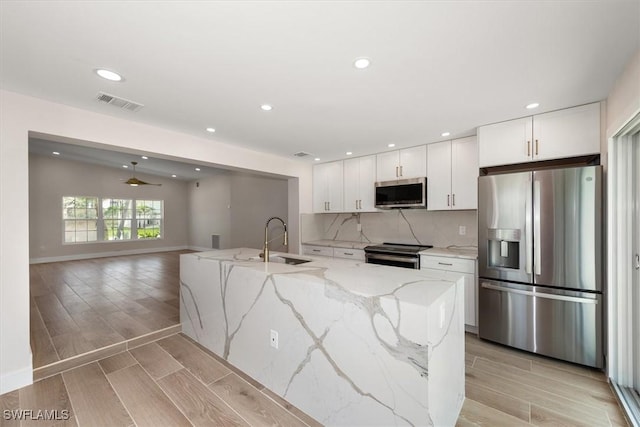 8336 Lagoon Rd, Fort Myers Beach, FL 33931 - kitchen with appliances with stainless steel finishes, white cabinets, wood finish floors, backsplash, and recessed lighting