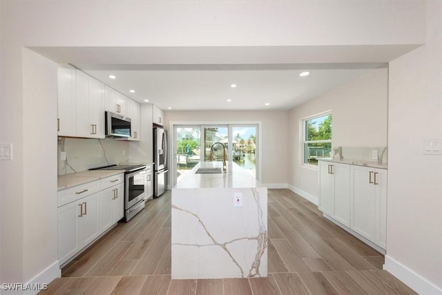 8336 Lagoon Rd, Fort Myers Beach, FL 33931 - kitchen with appliances with stainless steel finishes, white cabinets, light wood-type flooring, and recessed lighting