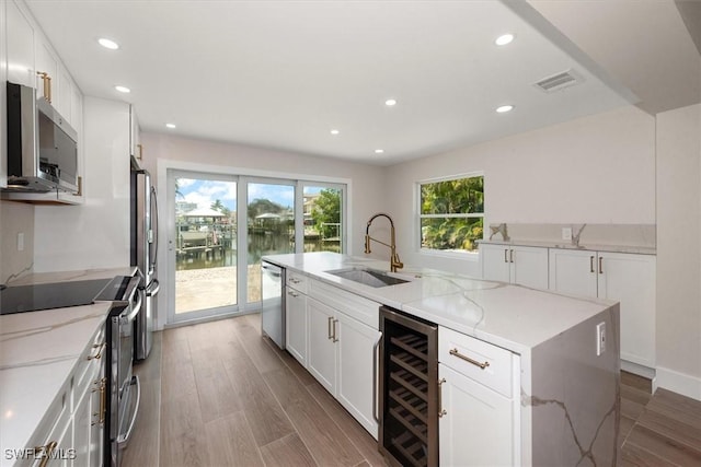 8336 Lagoon Rd, Fort Myers Beach, FL 33931 - kitchen with stainless steel appliances, beverage cooler, a center island with sink, recessed lighting, and white cabinets