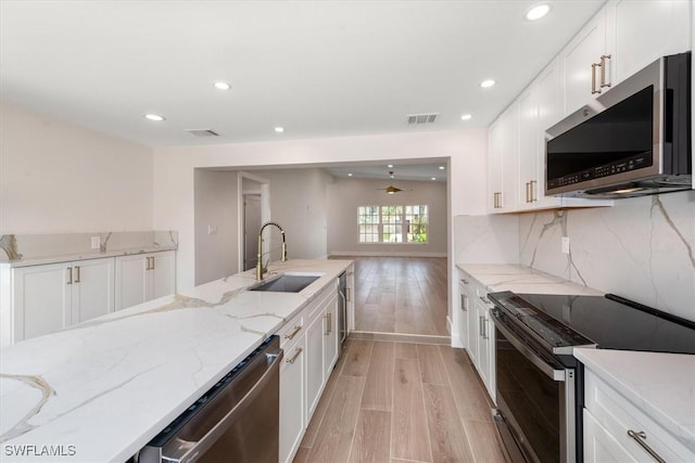 8336 Lagoon Rd, Fort Myers Beach, FL 33931 - kitchen with stainless steel appliances, light wood finished floors, recessed lighting, white cabinets, and light stone counters
