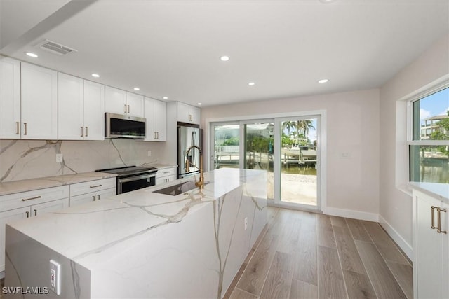 8336 Lagoon Rd, Fort Myers Beach, FL 33931 - kitchen with appliances with stainless steel finishes, backsplash, light wood-style floors, white cabinetry, and recessed lighting