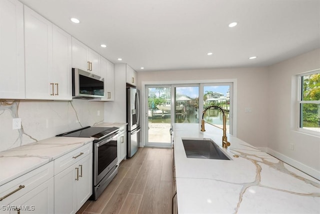 8336 Lagoon Rd, Fort Myers Beach, FL 33931 - kitchen with stainless steel appliances, recessed lighting, white cabinets, backsplash, and light stone countertops