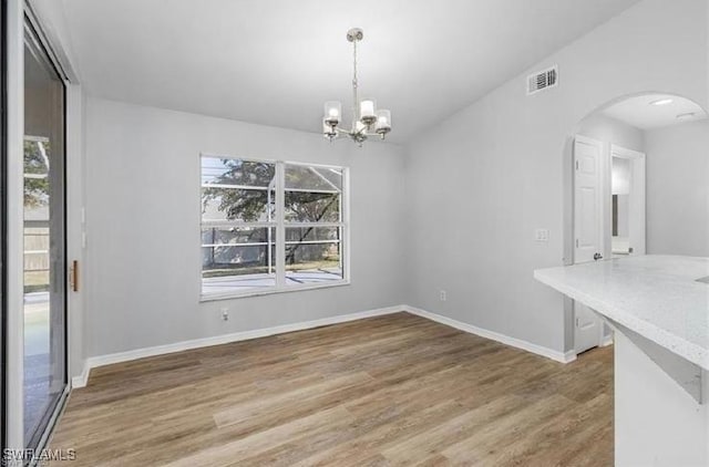609 SW 22nd St, Cape Coral, FL 33991 - unfurnished dining area with arched walkways, wood finished floors, and a chandelier